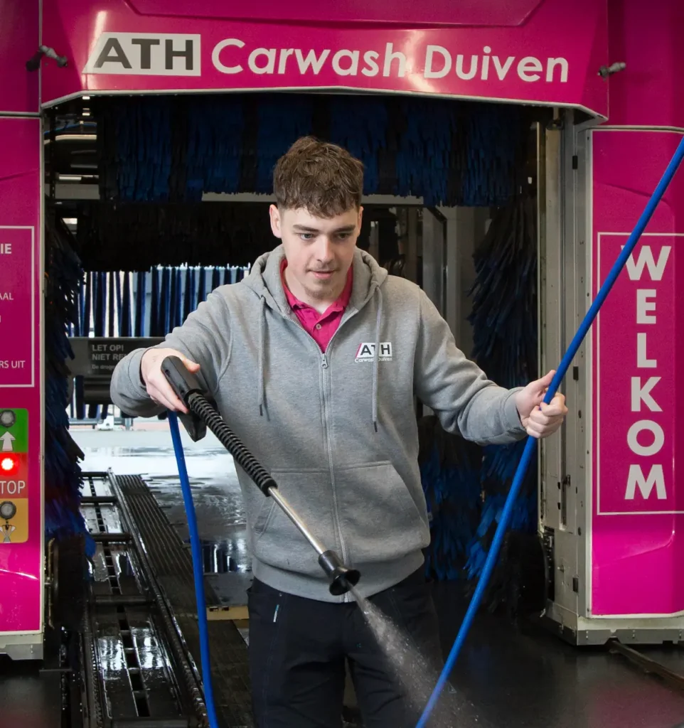 Medewerker in ATH Carwash Duiven gebruikt een hogedrukspuit.