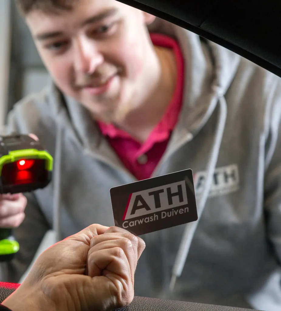 Een jongen scant een pas bij ATH Carwash Duiven.